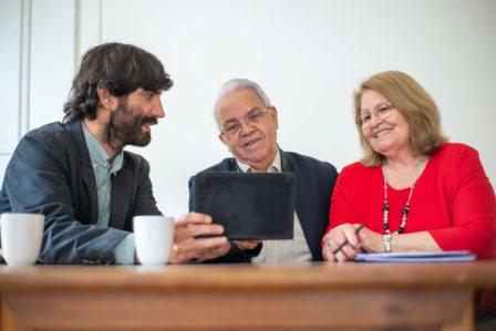 broker  advising a couple  about insurance/ investments sitting at a table